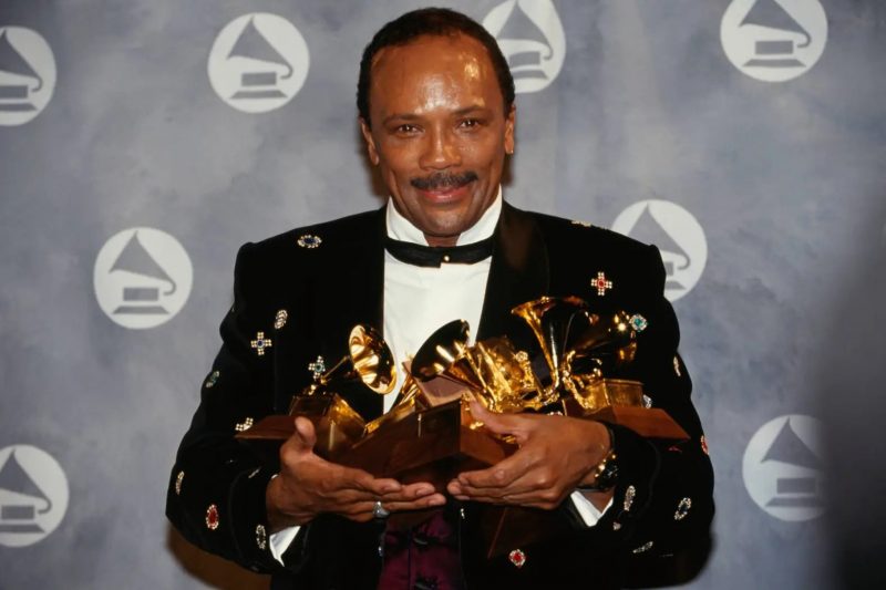 Quincy Jones segurando vários troféus do Grammy