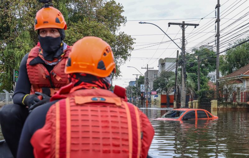 Bombeiros em bote resgatando pessoas na enchente 