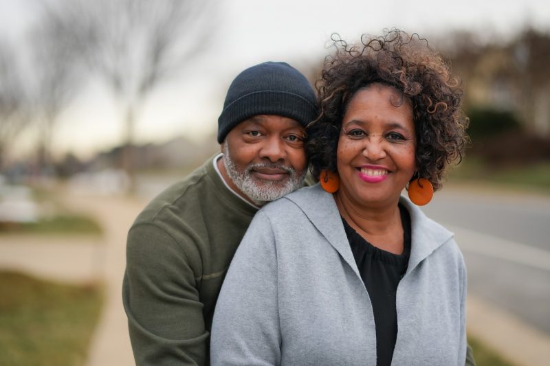 Casal idoso negro sorrindo em foto na rua 