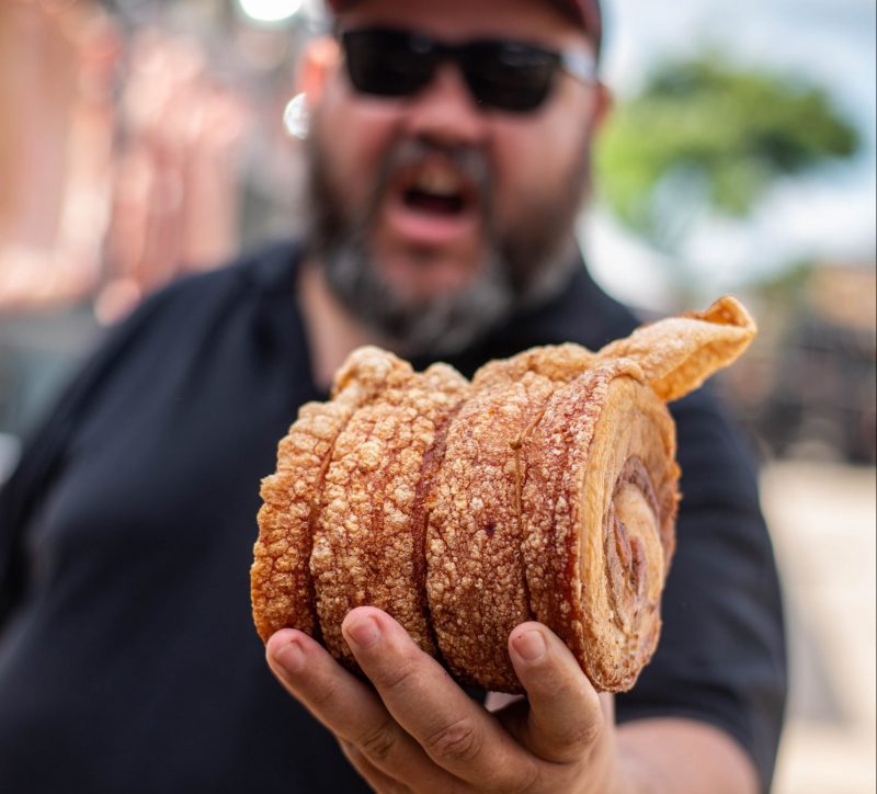 Foto mostra homem segurando um torresmo na Torresmofest