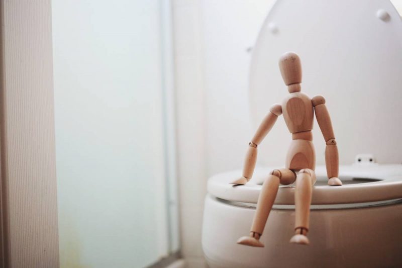 Boneco sentado no vaso sanitário