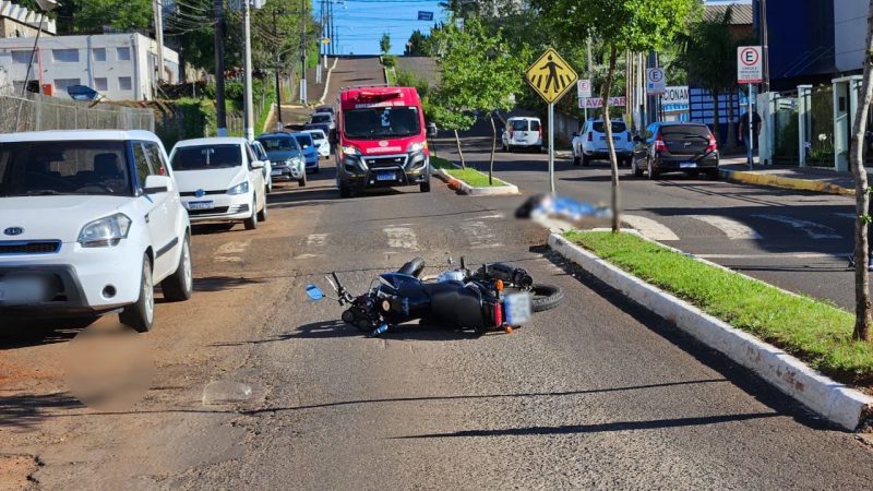 Moto de venezuelano caída sobre a via com corpo coberto ao fundo, sobre faixa de pedestre