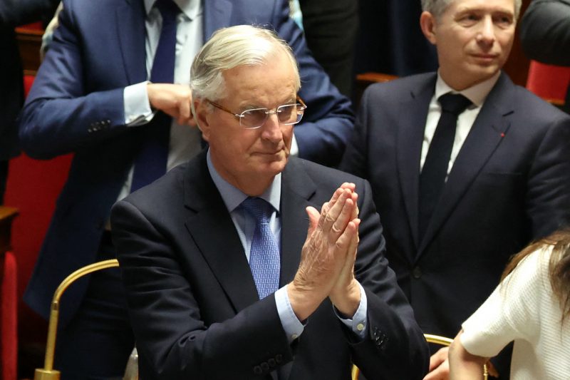 Foto mostra o primeiro-ministro Michel Barnier com as mãos unidas, sério enquanto olha para frente