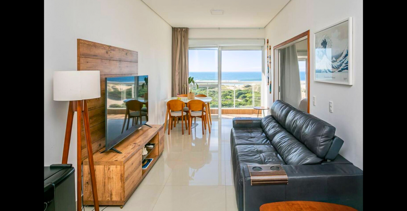 Sala e varanda integradas têm vista para o mar - Airbnb/Divulgação