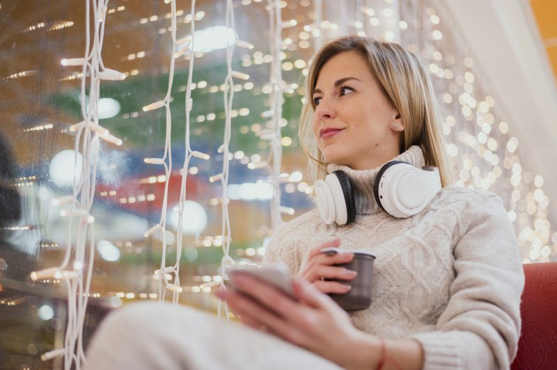 Mulher escutando meditação guiada no celular durante o Natal