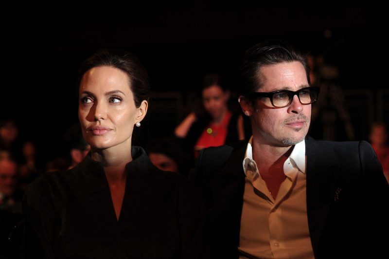 na foto casal Brad Pitt e Angelina Jolie aparecem juntos porém olhando cada um para um lado 