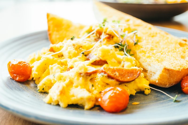 Ovos mexidos num prato junto com tomates e fatias de pão