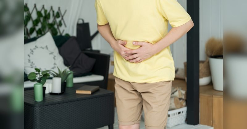 Pessoa com mãos na barriga em sala