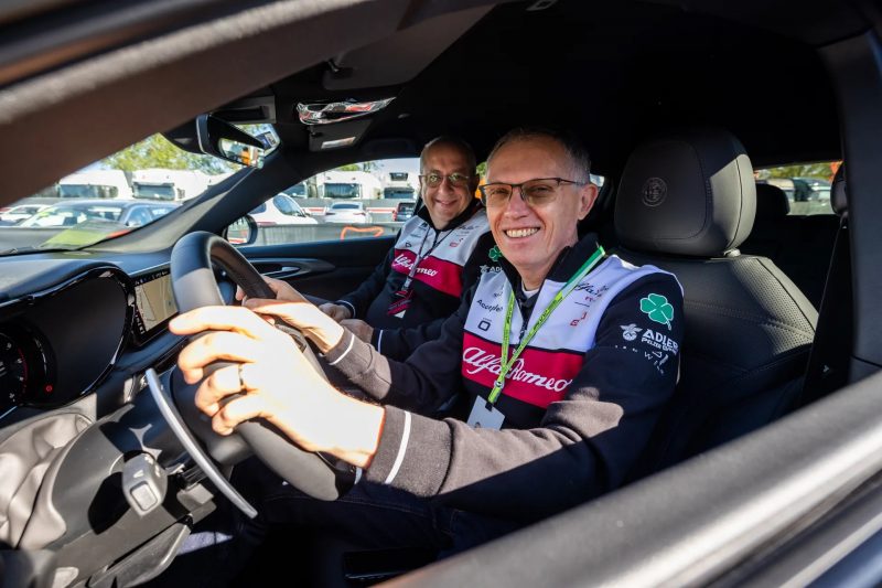 Carlos Tavares, ex CEO da Stellantis, posando para foto dentro de carro e acompanhado de outro executivo