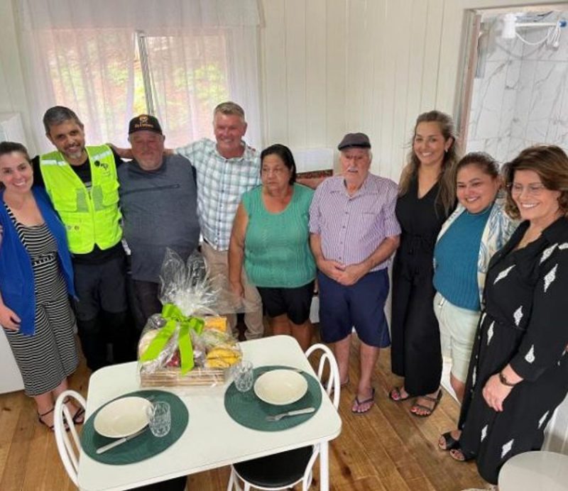 Casal de idosos com família e amigos durante entrega de casa