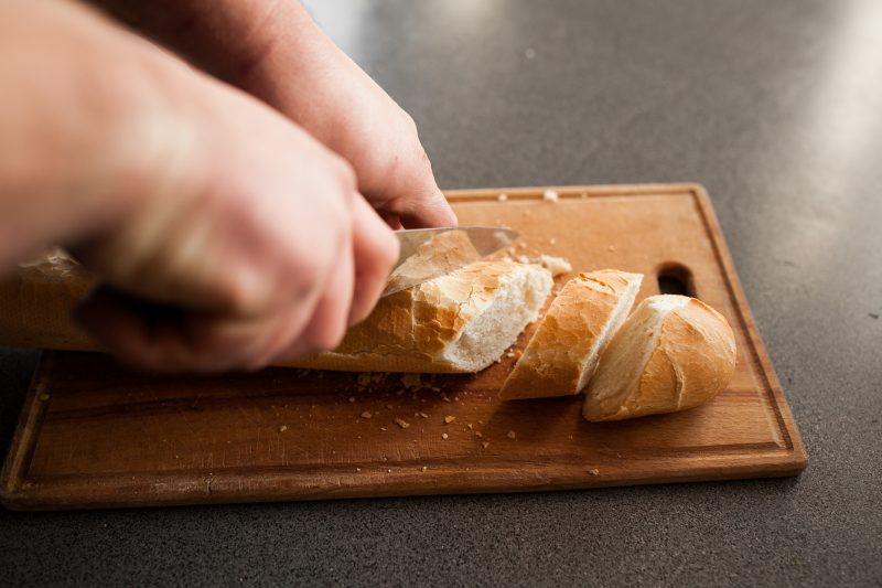 Homem cortando um pão em fatias