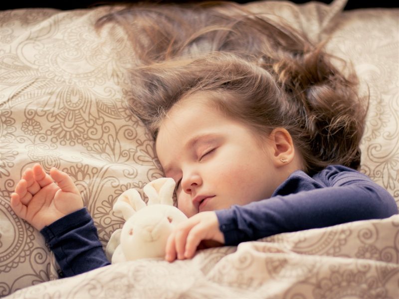 Menina dormindo tranquilamente com seu coelho de pelúcia