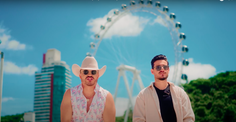 Trecho do clipe "Descer pra BC" em que dupla canta em frente a uma roda-gigante 