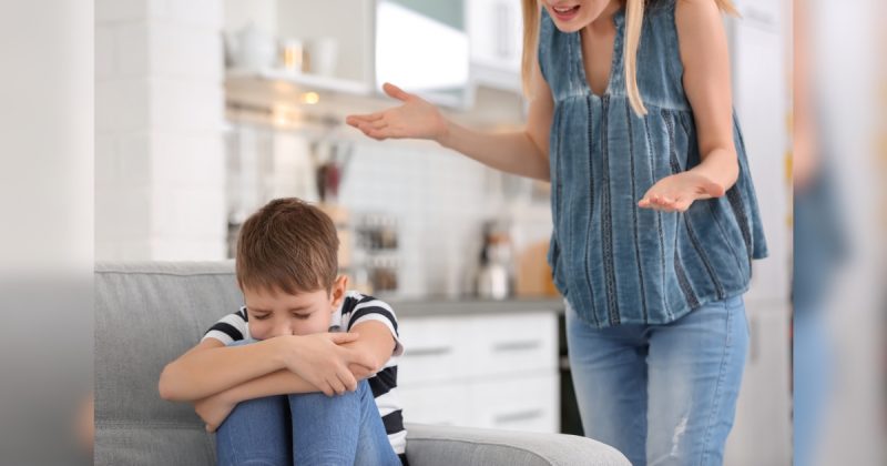 Mulher brigando com menino que está sentado no sofá