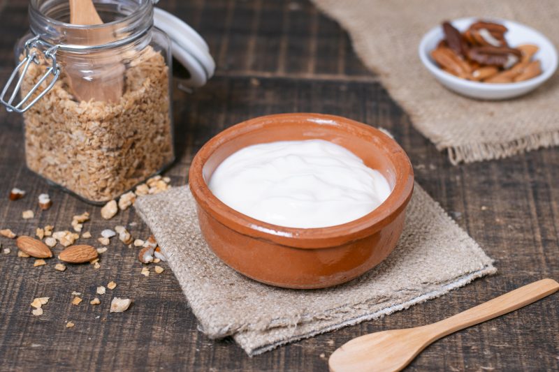 Iogurte natural em uma tigela com cereais ao lado 