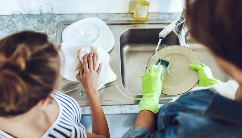 Casal lavando a louça e secando