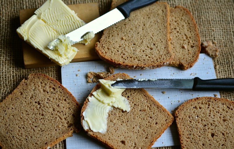 fatias de pão com uma faca passando manteiga nelas 