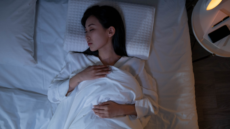 mulher asiática dormindo na cama em quarto com luz baixa