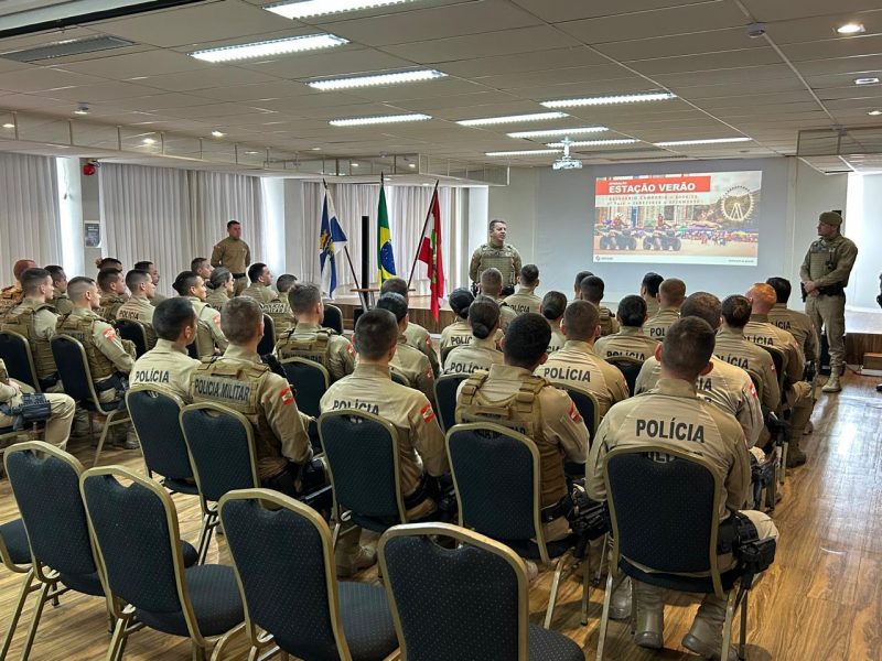 Na foto, policiais militar de costa e sentados. Vão reforças a segurança de Balneário Camboriú na temporada. 