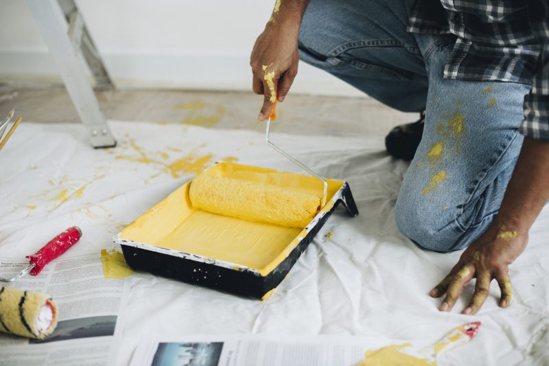 Homem pintando as paredes com a tinta amarela 