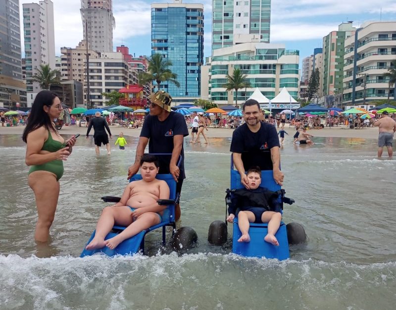 Imagem mostra duas crianças tomando banho de mar com acessibilidade em Itapema