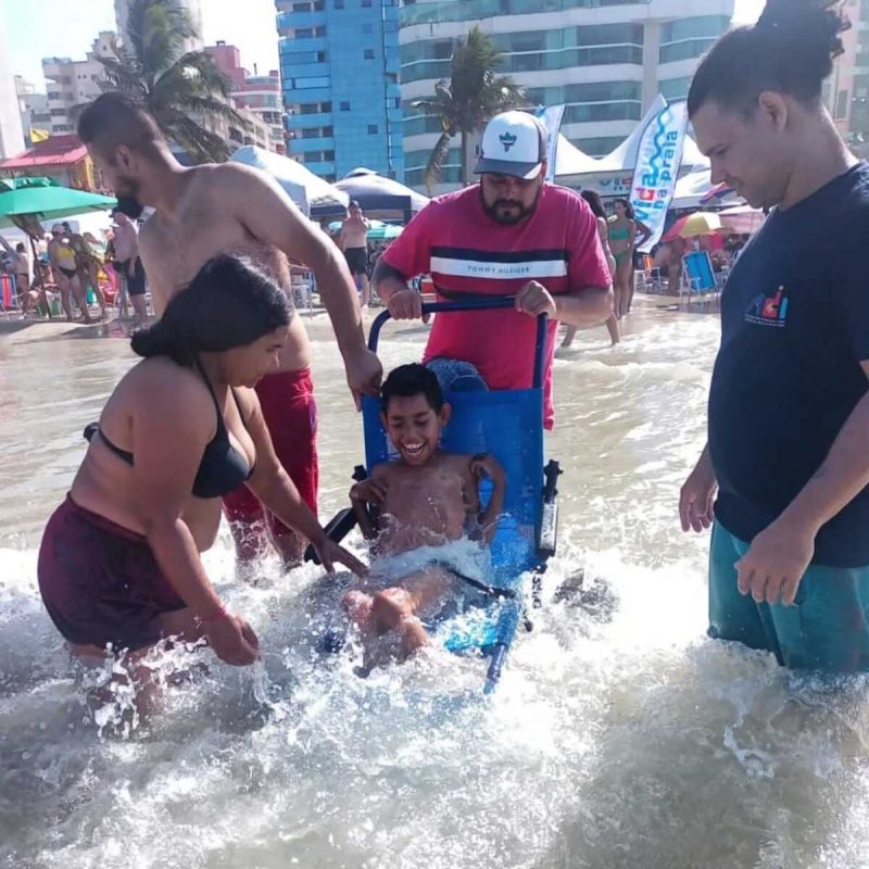 Imagem mostra criança tomando banho de mar com acessibilidade em Itapema