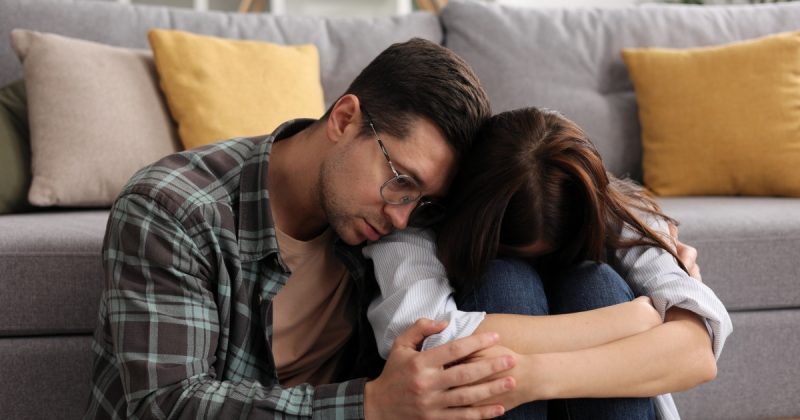 Homem abraçando mulher que está com cabeça entre as pernas