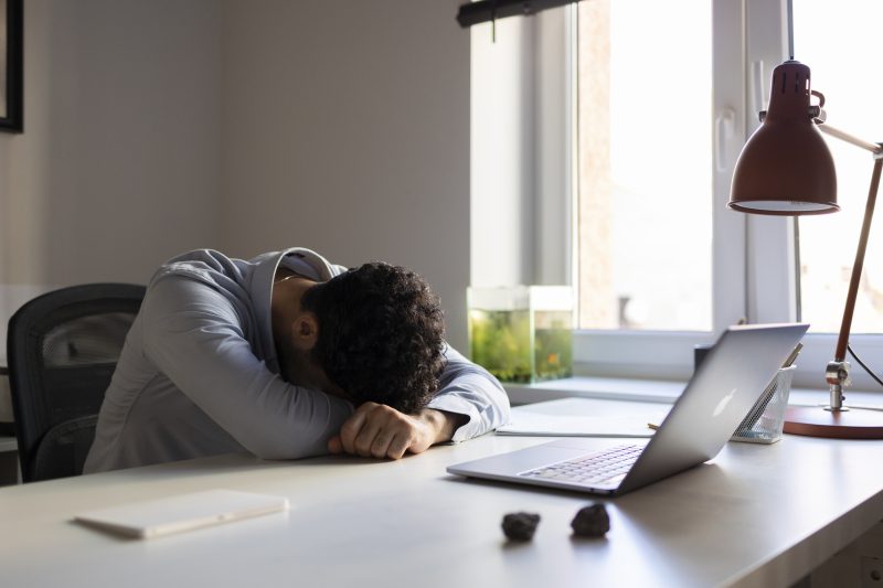 Homem cansado com a cabeça sobre a mesa 