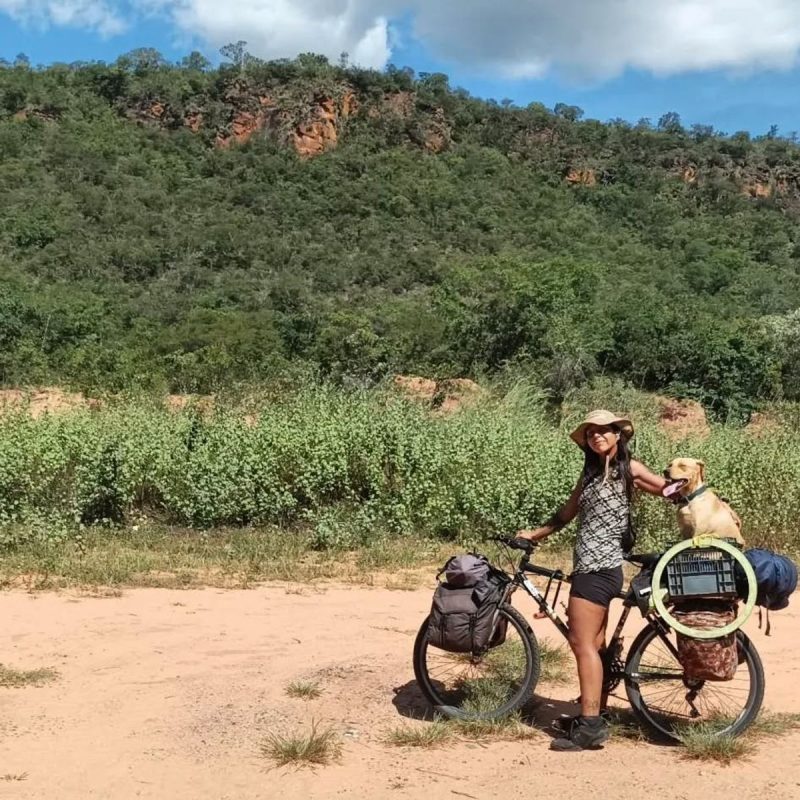 Turista em bicicleta acompanhada de vira-lata caramelo 