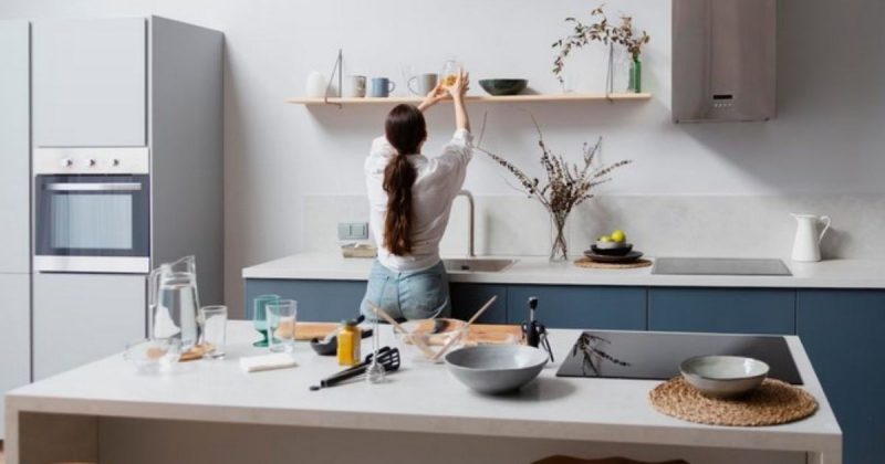 Cozinha com copa e uma mulher mexendo em um pote na prateleira