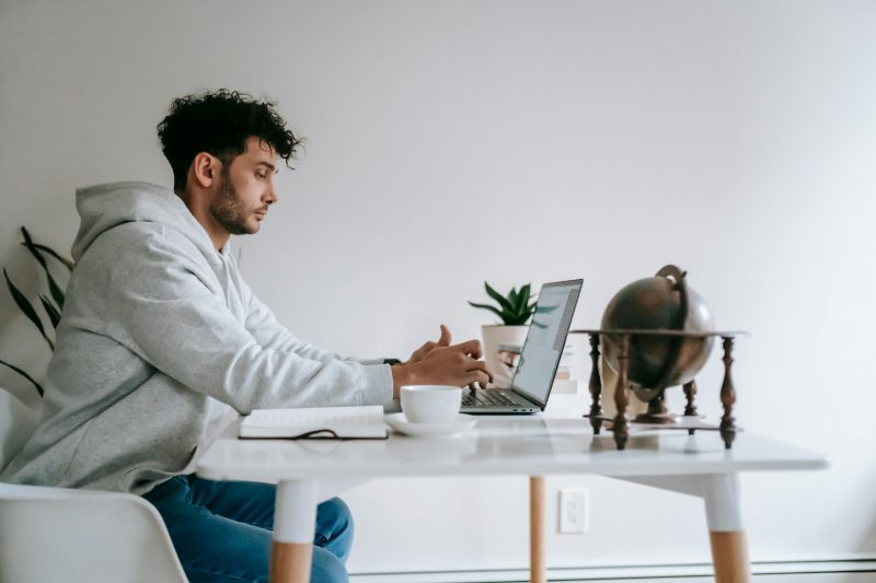 Homem em frente ao notebook em uma sala de casa 