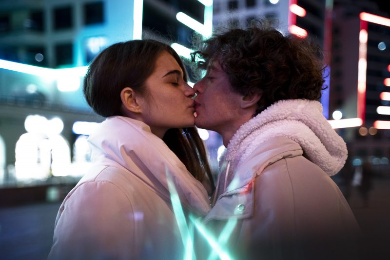 Casal se beijando em um a rua bem iluminada