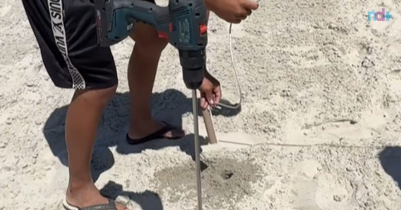 Imagem mostra homem fazendo furo de parafusadeira na praia de Balneário Camboriú