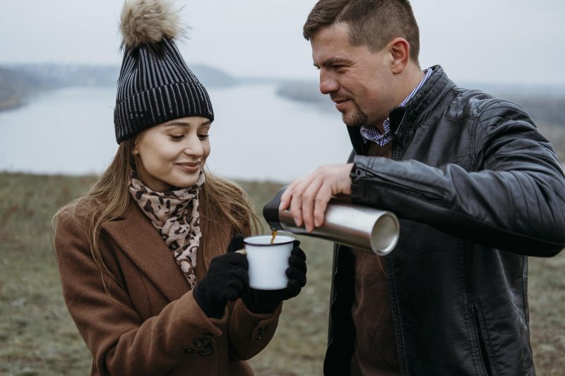 Casal em uma montanha tomando café 