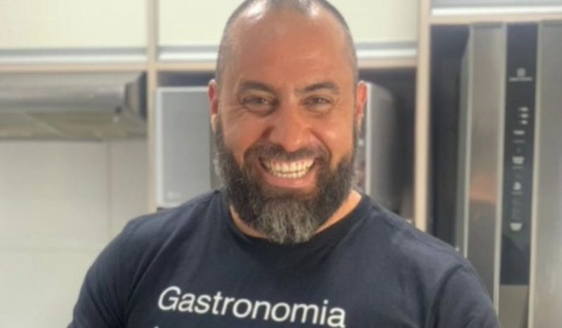 Chef de cozinha catarinense é preso suspeito de estuprar menina de 12 anos, foto mostra homem com cabelo curto, camiseta preta escrita "gastronomia", sorrindo para a foto