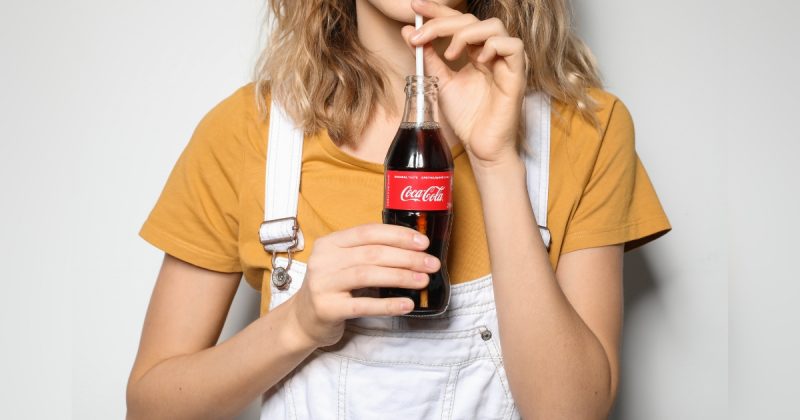 Pessoa segurando Coca-Cola com canudinho