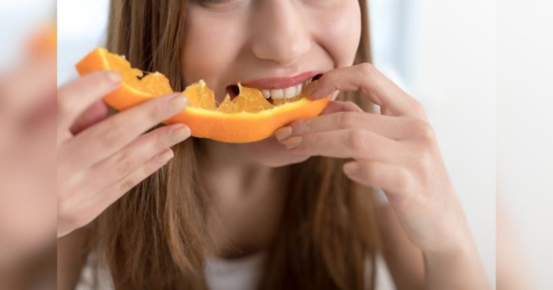 Mulher comendo laranja