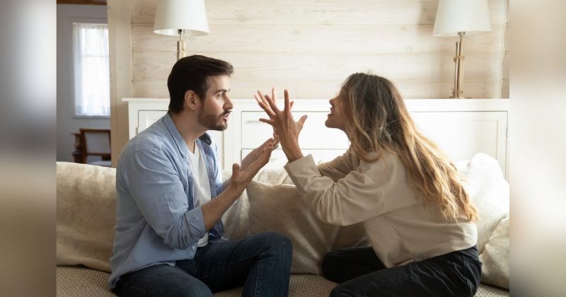 Casal discutindo em sofá de casa