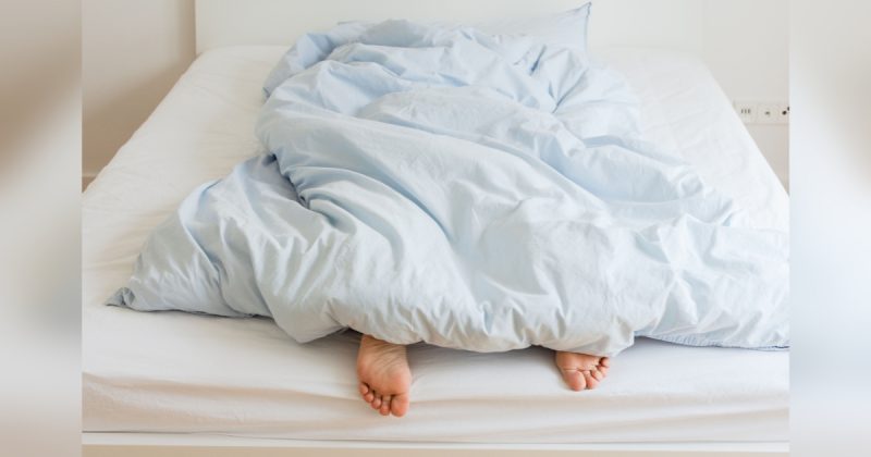 Mulher debaixo das cobertas com pés para baixo