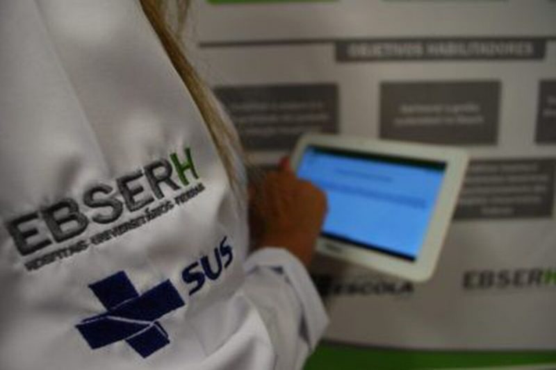 médica com jaleco do SUS mexendo em tablet