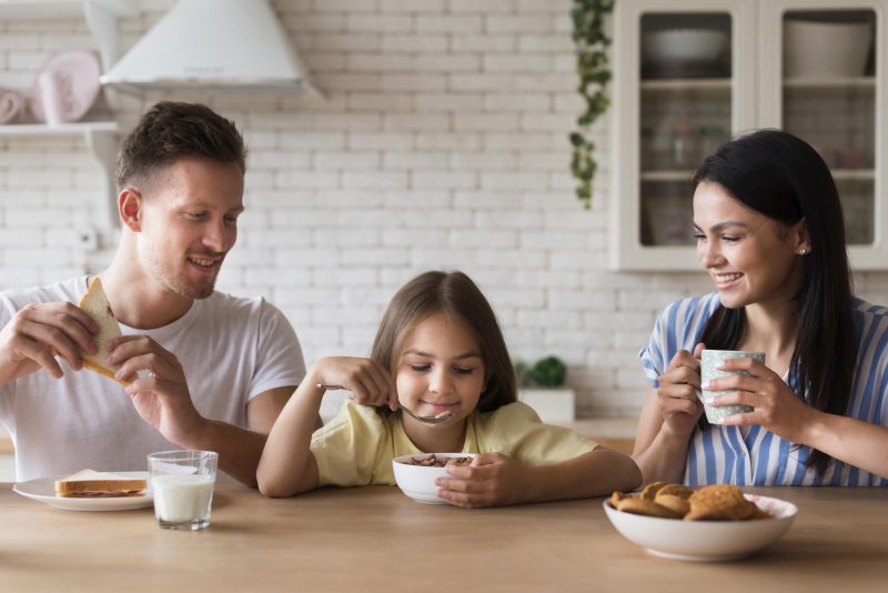 Família com mãe, pai e filha tomando café da manhã 