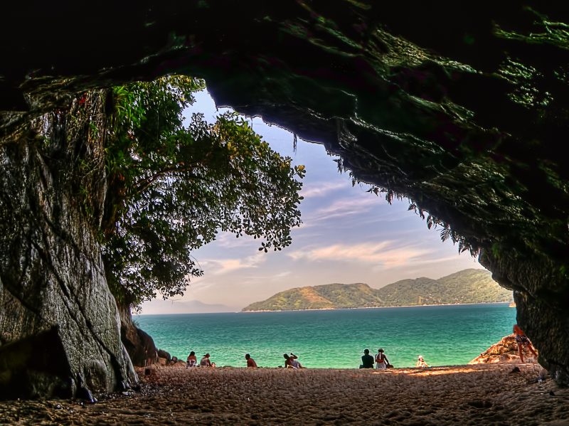 Gruta de pedras com vista para uma praia de águas cristalinas 