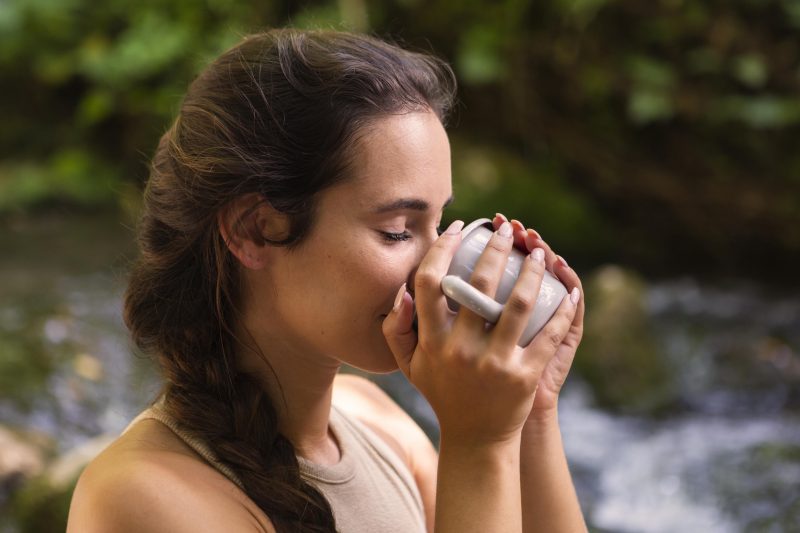 Mulher bebendo água em uma caneca 