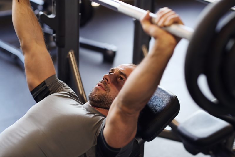 Homem levantando uma barra com peso na academia 