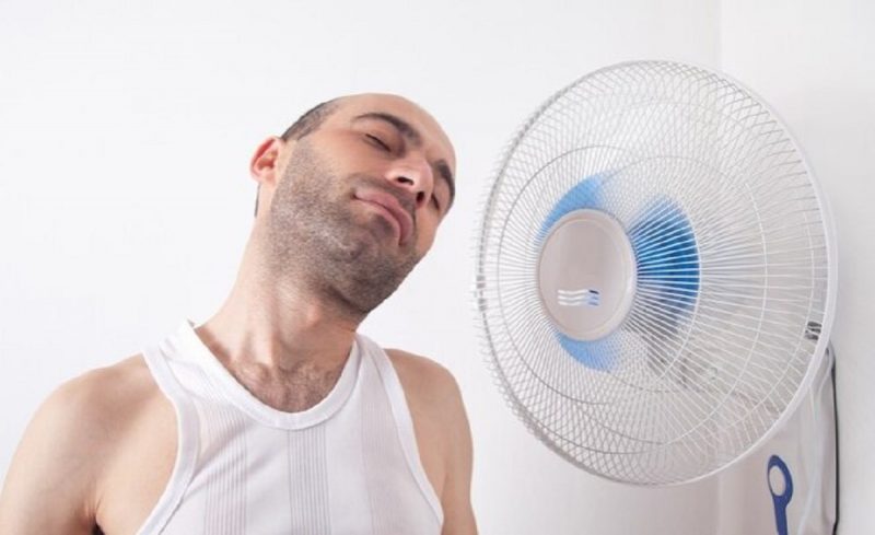 na foto aparece um homem que tenta esfriar a casa com um ventilador