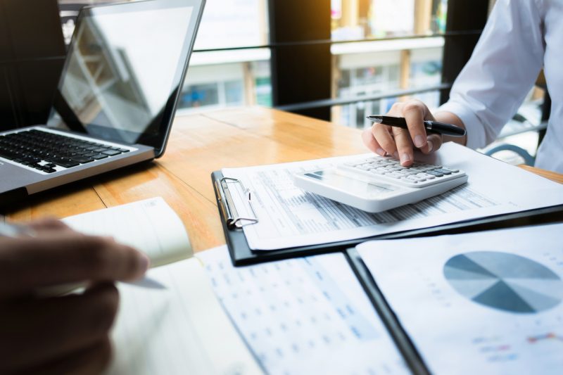 homem faz contas em calculadora em meio a planilhas de dados em um local de trabalho