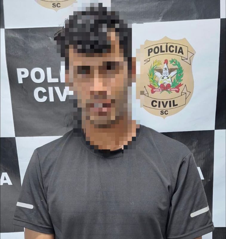 Foto mostra suspeito de homicídio com rosto borrado na delegacia