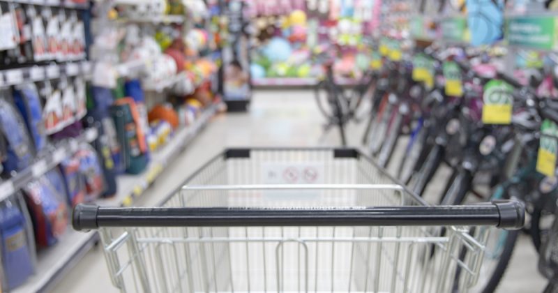 Carrinho de supermercado em corredor com bicicletas e outros produtos não identificáveis