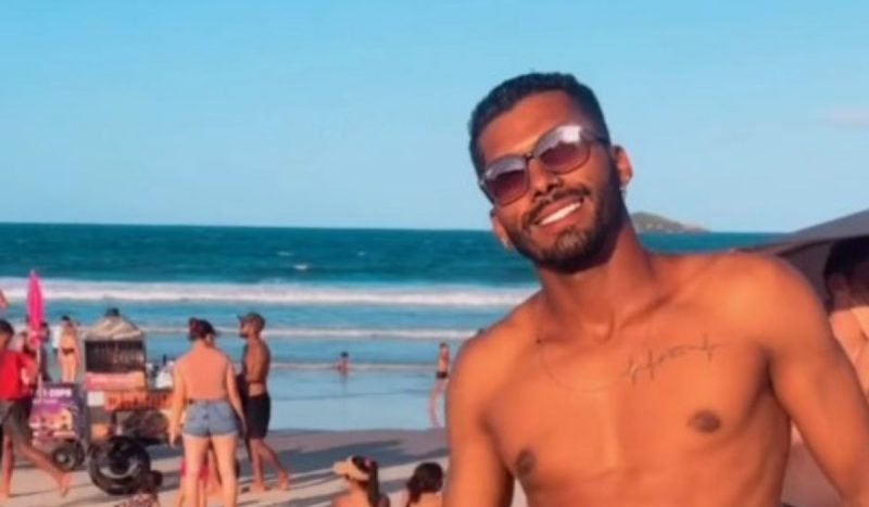 Deivison morreu afogado na praia dos Ingleses, em 1º de janeiro, foto mostra homem sorrindo com praia e pessoas ao fundo