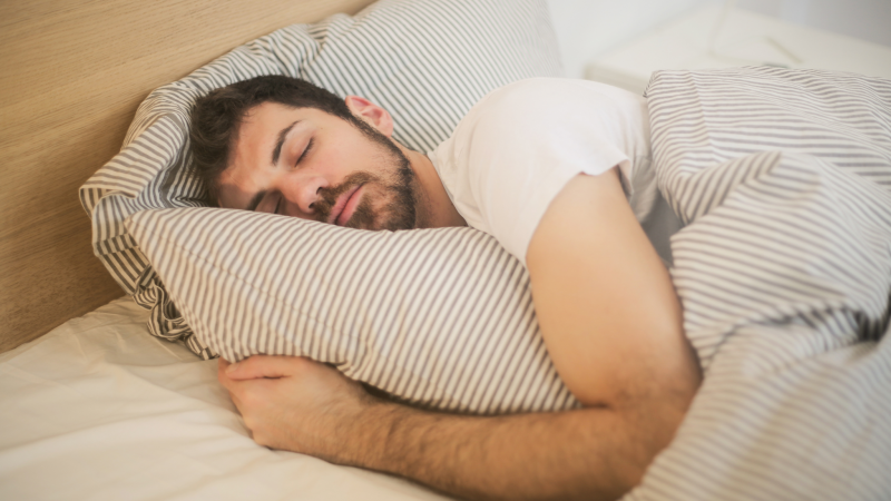 Homem dormindo confortavelmente em uma cama 